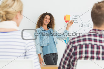 Smiling young designer presenting ideas to her colleagues