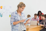 Smiling young designer using her tablet in front of her colleagues