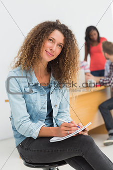 Thinking designer sitting in front of her colleagues using digital tablet