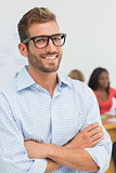 Attractive designer smiling at camera with colleagues behind him