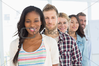 Diverse design team standing in a line smiling at camera