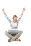 Pretty blonde cheering at camera with laptop sitting on floor