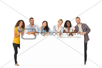 Smiling group of young friends leaning on large poster