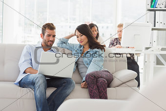 Young smiling designers working on laptop on the couch