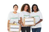 Team of volunteers smiling at camera holding donations boxes