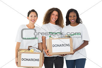 Team of volunteers smiling at camera holding donations boxes