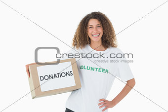 Smiling volunteer holding a box of donations with hand on hip