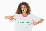 Smiling volunteer pointing to her tshirt looking at camera