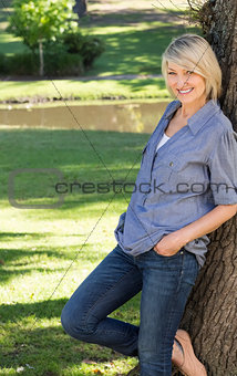 Woman leaning on tree trunk in park