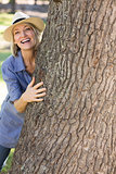 Woman hiding behind tree trunk
