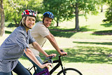 Smiling couple riding bicycles in park