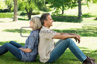 Couple sitting back to back in park