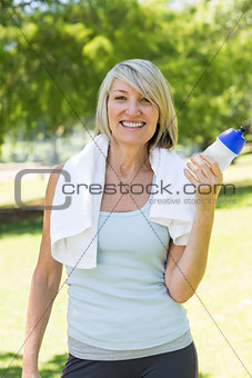 Happy woman holding water bottle in park