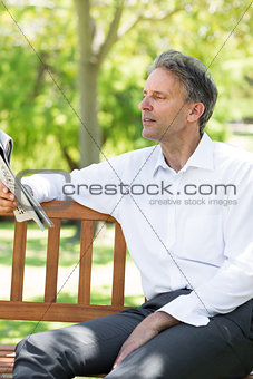Businessman reading newspaper at park