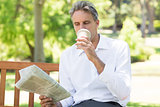 Businessman drinking coffee while reading newspaper