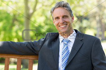 Confident businessman sitting on park bench