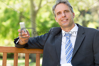 Businessman with cellphone at park