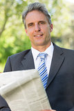 Mature businessman with newspaper in park