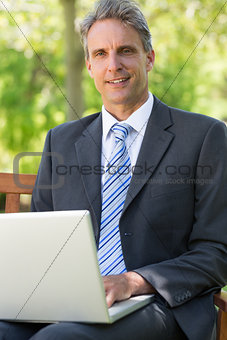 Thoughtful businessman with laptop at park