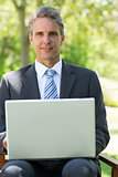 Confident businessman with laptop at park