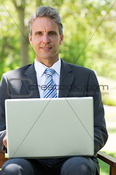 Confident businessman with laptop at park