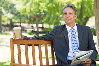Thoughtful businessman with newspaper and coffee cup