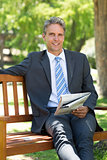 Businessman with newspaper sitting in park
