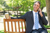 Businessman with disposable cup answering cellphone