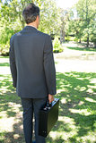 Businessman carrying briefcase in park