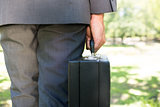 Midsection of businessman carrying briefcase