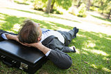 Businessman resting head on briefcase