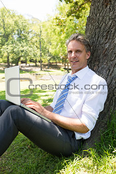 Confident businessman with laptop in park