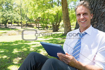 Businessman with digital tablet in park