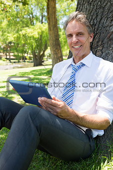 Confident businessman with digital tablet in park