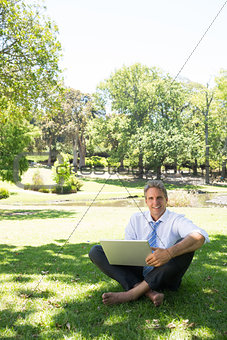 Businessman with laptop sitting in park