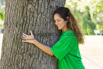 Beautiful environmentalist embracing tree trunk