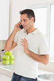Handsome man using mobile phone in kitchen