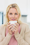 Beautiful young woman with coffee cup in kitchen
