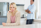 Thoughtful woman with man standing in background at kitchen
