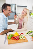 Cheerful couple with chopped vegetables in kitchen