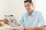 Casual man with newspaper looking away in kitchen