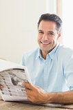 Smiling casual man with newspaper in kitchen