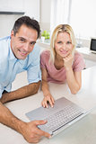 Smiling couple using laptop in kitchen