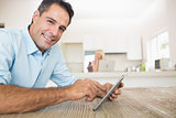 Portrait of smiling man using digital table in kitchen