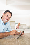 Portrait of a smiling man using digital table in kitchen