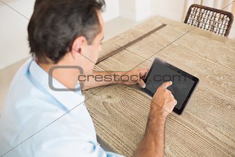 Concentrated man using digital table in kitchen
