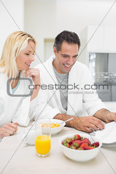 Couple having breakfast while reading newspaper in kitchen