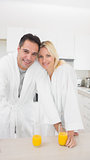 Smiling couple with orange juice glasses in kitchen