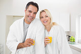 Smiling couple with orange juice glasses in kitchen