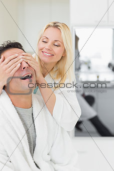 Smiling woman covering happy mans eyes